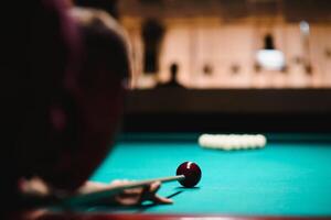 the player takes aim at the ball in Billiards photo