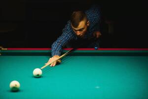 the player takes aim at the ball in Billiards photo