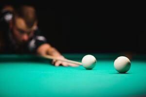 the player takes aim at the ball in Billiards photo