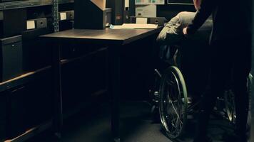 Inspector wheelchair user analyzes geographical maps or data for crime scene reconstructions, helping his colleagues with details in events timeline. Senior detective with disability. Camera A. video