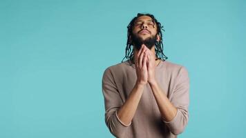 Pious middle eastern man praying to his god, asking for forgiveness, feeling desperate. Spiritual BIPOC man doing worship hand gesturing, confessing, begging for pardon, studio background, camera A video