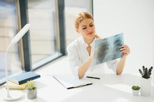 Woman doctor hands holding patient chest x-ray film before treatment.Image lung at radiology department in hospital.Covid-19 scan body xray test detection for covid virus epidemic spread concept photo