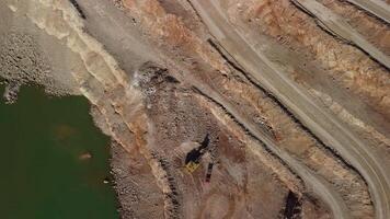 Aerial view of industrial opencast mining quarry with lots of machinery at work - extracting fluxes for the metal industry. Oval mining industrial crater, acid mine drainage in rock. video