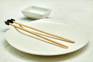 Wooden chopsticks for the inept. Oriental food, sushi, plate, gravy bowl photo