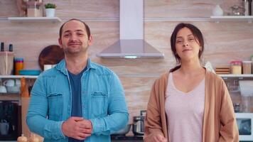 retrato de casado Pareja sonriente a cámara en hogar cocina. Cocinando preparando sano orgánico comida contento juntos estilo de vida. alegre comida en familia con vegetales video