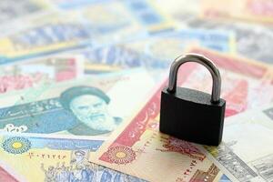 Small padlock lies on pile of iranian money. Sanctions, ban or embargo concept photo