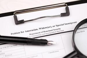 I-360 Petition for Amerasian, Widower or special immigrant blank form on A4 tablet lies on office table with pen and magnifying glass photo