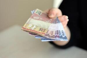 Brazilian money bills in woman hand. Female gives bunch of brazilian reais to us photo