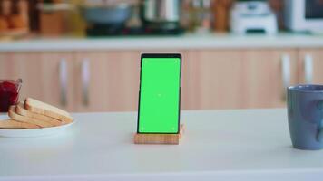 Phone with chroma key in empty modern kitchen. Green screen chroma mock up isolated mockup background ready to be replaced with your text, logo or advertisement. Using internet, social networks and browsing video