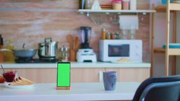 téléphone avec copie espace disponible suivant à tasse de café dans cuisine avec personne dans. vert écran chrominance moquer en haut isolé maquette Contexte prêt à être remplacé avec votre texte, logo ou publicité. en utilisant l'Internet, social réseaux et navigation video