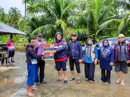 pariaman, Indonesia - marzo 8, 2024. Sres. regional secretario de pariaman ciudad manos terminado comida ayuda a inundar víctimas en norte pariaman distrito foto