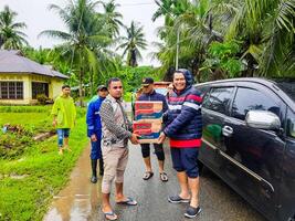 pariaman, Indonesia - marzo 8, 2024. Sres. regional secretario de pariaman ciudad manos terminado comida ayuda a inundar víctimas en norte pariaman distrito foto