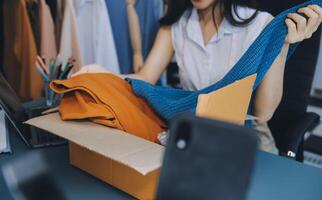 Beautiful asian woman blogger showing bag in front of camera to recording vlog video live streaming at her shop.Business online influencer on social media concept. photo