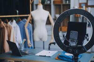 Beautiful asian woman blogger showing bag in front of camera to recording vlog video live streaming at her shop.Business online influencer on social media concept. photo