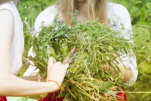 Hands weave a wreath of wild flowers and herbs. photo