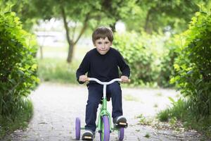 The boy on a tricycle.Child preschooler spin the pedals on a toy bicycle photo