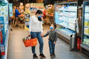 madre y hijo son compras a el tienda de comestibles almacenar. ellos vestir mascaras durante cuarentena. coronavirus pandemia .coved-19 destello. el epidemia de el virus. foto