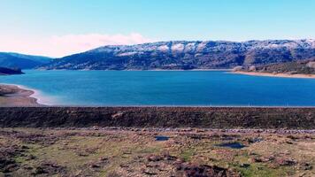 Serene lake with snow-dusted mountains in the backdrop, national park Mavrovo in Macedonia, view from the top, aerial video