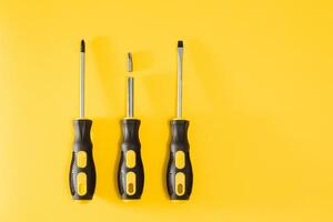 three black and yellow screwdrivers on a yellow background with space for text. Tools, construction and workshop, home repairs, slusar work photo