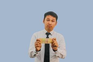 Adult Asian man showing sad expression while holding small amount of money photo