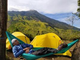 Mojokerto, Indonesia, 04 November 2020 - A man rests in a hammock on Mount Pundak, Mojokerto photo