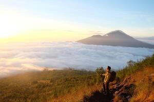 Above Cloud Nine, Mount Batur's Peak, Asian Man Trekker under Azure Sky and Cloud Sea photo