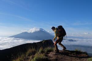 Above Cloud Nine, Mount Batur's Peak, Asian Man Trekker under Azure Sky and Cloud Sea photo