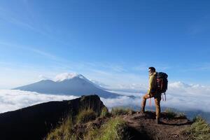 Above Cloud Nine, Mount Batur's Peak, Asian Man Trekker under Azure Sky and Cloud Sea photo