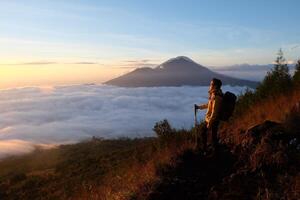 Above Cloud Nine, Mount Batur's Peak, Asian Man Trekker under Azure Sky and Cloud Sea photo