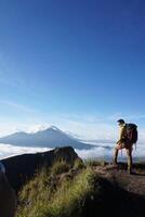 Above Cloud Nine, Mount Batur's Peak, Asian Man Trekker under Azure Sky and Cloud Sea photo