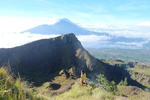 encima nube nueve, montar batur cima, asiático hombre excursionista debajo azur cielo y nube mar foto