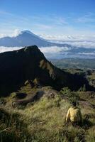 encima nube nueve, montar batur cima, asiático hombre excursionista debajo azur cielo y nube mar foto