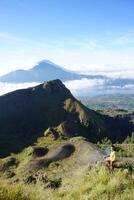 encima nube nueve, montar batur cima, asiático hombre excursionista debajo azur cielo y nube mar foto