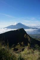 Above Cloud Nine, Mount Batur's Peak, Asian Man Trekker under Azure Sky and Cloud Sea photo