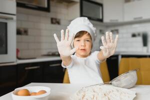 Little boy in kitchen.Cute boy wears a chef hat and apron. photo