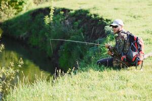 hombre relajante y pescar por junto al lago fines de semana hecho para pesca. pescador masculino pasatiempo. Maestro cebo. mantener calma y pescado en. pescador tejido a ganchillo girar dentro el río esperando grande pez. chico mosca pescar foto