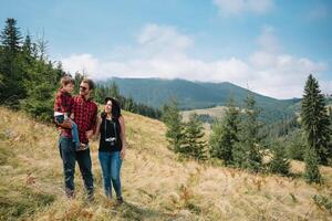 familia permanecer en el parte superior de montaña, mirando en el hermosa vista. foto