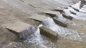 row of chute dentate blocks in concrete water spillway channel slope slowing down the flow of water running down video