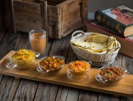 Assorted break fast set balalet or balaleet, aloo nakhi,aloo karahi, tomato egg, foul medames with bread and coffee served in a dish isolated on cutting board side view of breakfast on background photo