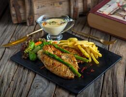 chicken steak with fries isolated on cutting board on wooden background side view of steak photo