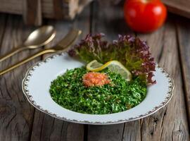 Fresh tabouleh salad or tabbouleh served in a dish isolated on wooden background side view photo