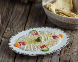 moutable hummus served in a dish isolated on wooden background side view of appetizer photo