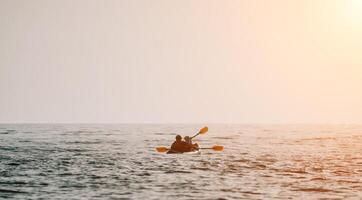 contento Pareja kayaks en un inflable kayac en el mar a puesta de sol. Pareja piragüismo en el mar cerca el isla con montañas. personas kayak en vida chaquetas navegar. espalda ver foto