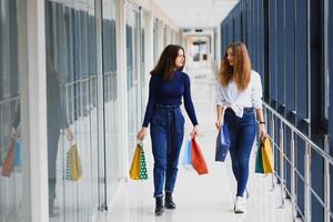 Two girl-friends on shopping walk on shopping centre with bags photo