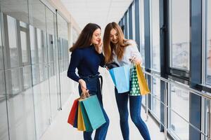 Two girl-friends on shopping walk on shopping centre with bags photo