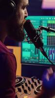 Vertical Video Music producer singing at home studio microphone to record songs, editing and adjusting volume levels in post production. Audio engineer conducts recordings of vocals, mixing console. Camera A.