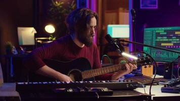 la musique producteur en chantant chanson et en jouant acoustique guitare, travail dans le sien personnel Accueil studio à record une Nouveau mélodie. l'audio ingénieur enregistrement des airs, édition avec mélange console table d'harmonie. caméra un. video