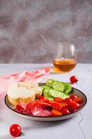 Girl dinner of smoked sausage, cucumbers, cherry tomatoes and buns on a plate vertical view photo