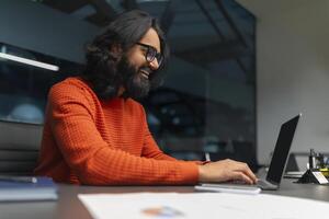 Joyful man typing on a laptop in the office photo