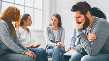 Depressed man sitting at rehab group therapy photo